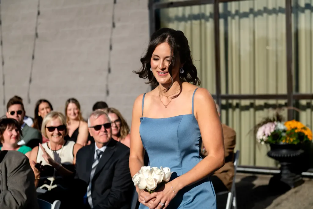 a bridesmaid walks down the sunny aisle while laughing. Shot at Carmen's event centre, Hamilton by Pixelesque Photography.