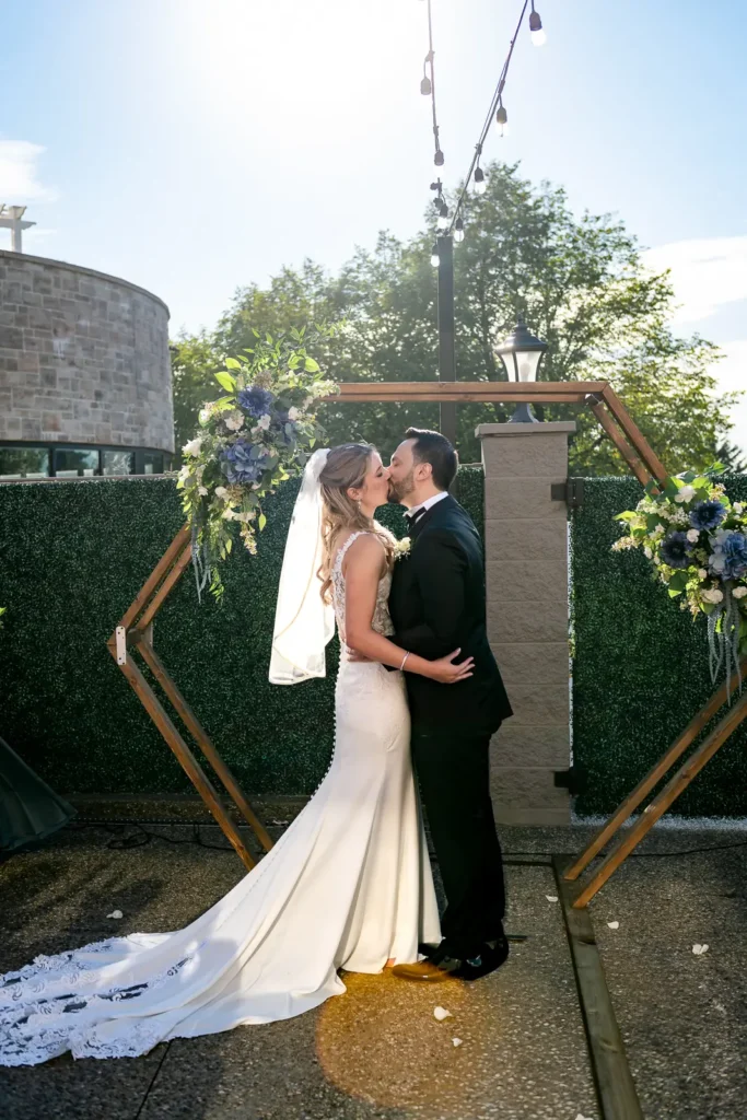 the sun bursts behind the couple as they share their first kiss. Shot at Carmen's event centre, Hamilton by Pixelesque Photography.