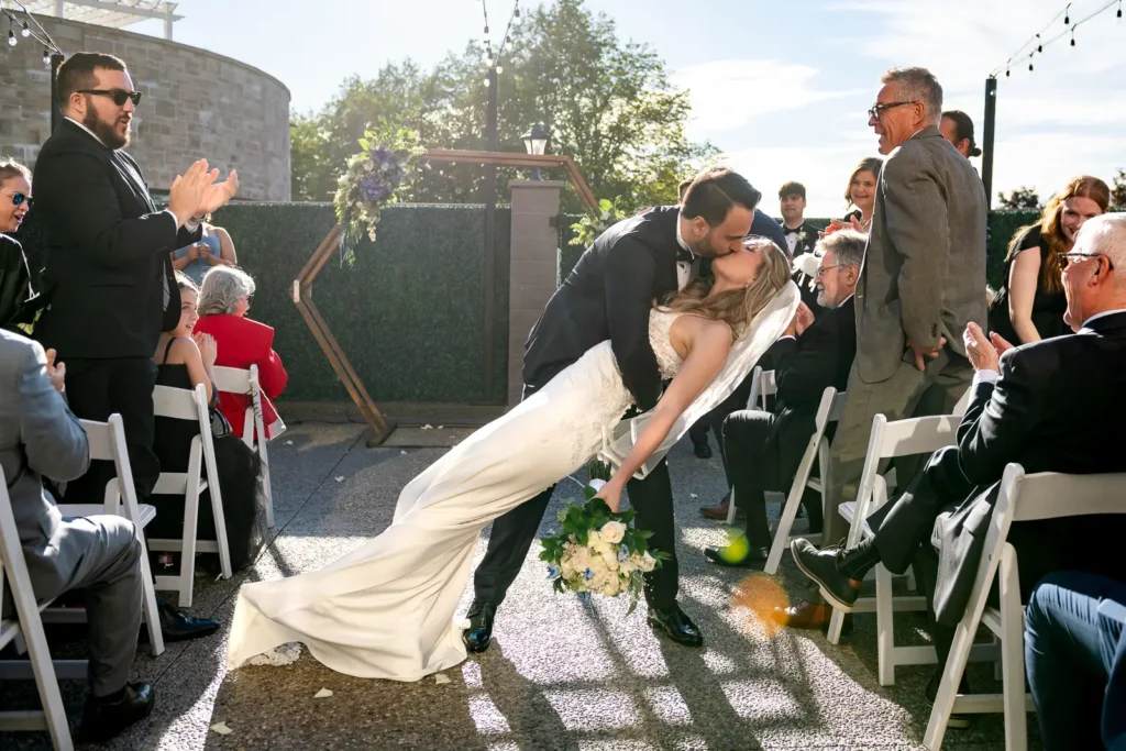the groom dips and kisses his bride as they walk down the aisle. Shot at Carmen's event centre, Hamilton by Pixelesque Photography.