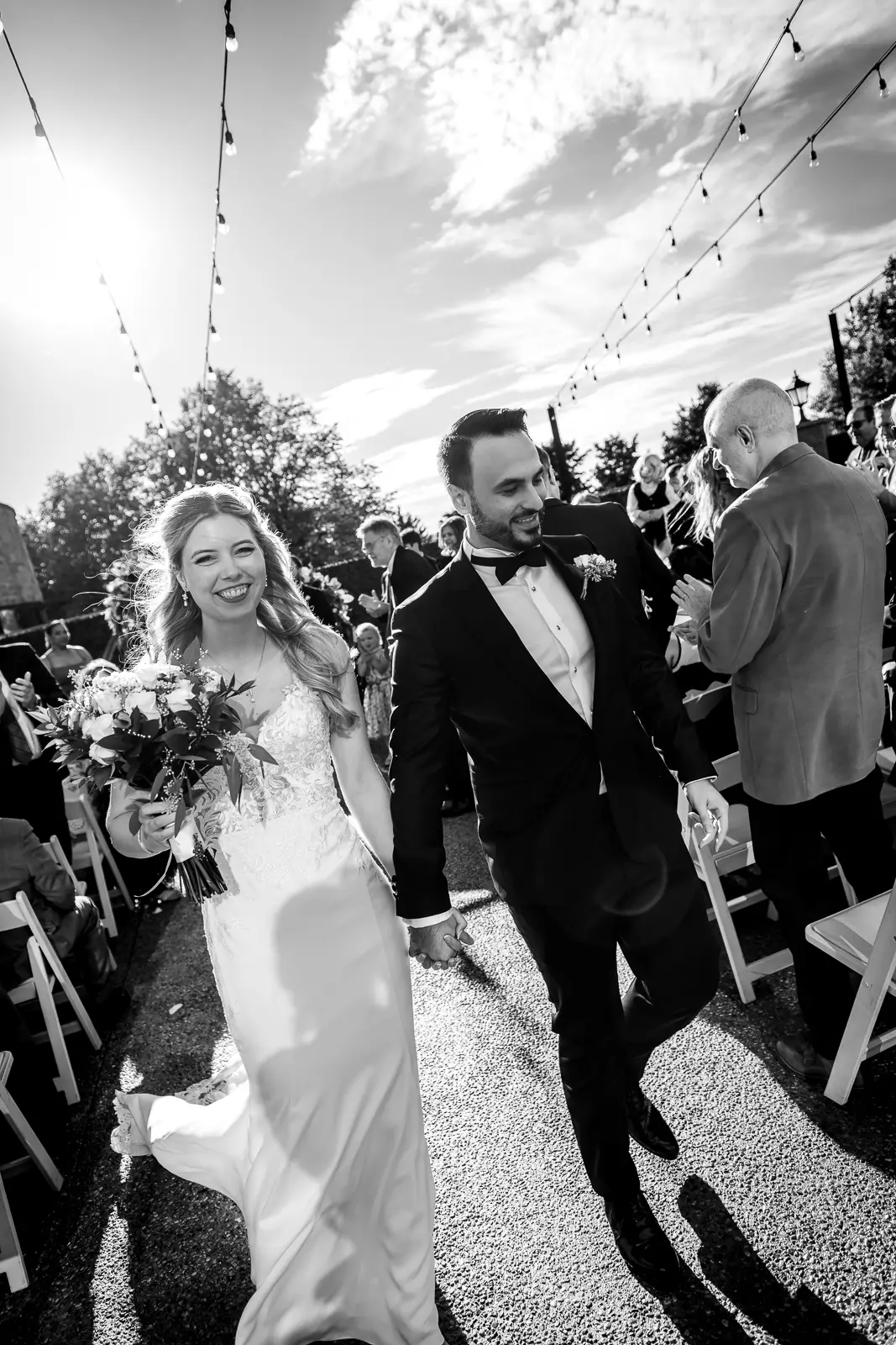 the bride smiles at the camera as she and her groom leave the ceremony. Shot at Carmen's event centre, Hamilton by Pixelesque Photography.