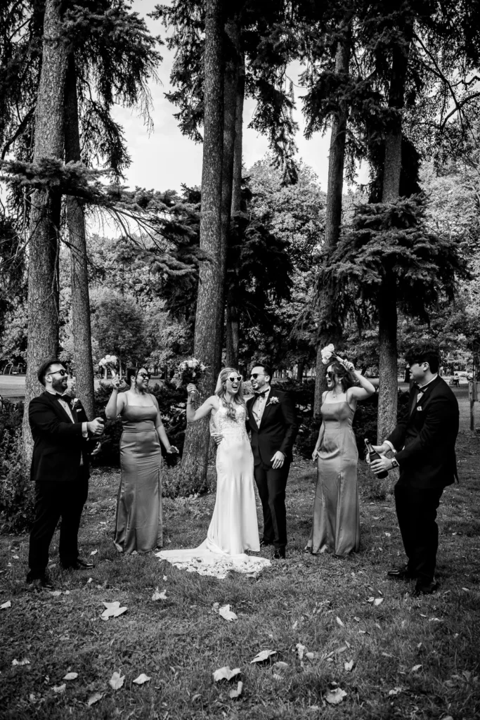 the couple and bridal party cheer as champagne sprays around. Shot at Hamilton's Gage Park by Pixelesque Photography.