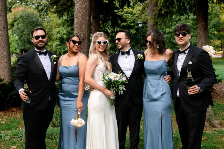 the bridal party all look around at each other and laugh. Shot at Hamilton's Gage Park by Pixelesque Photography.