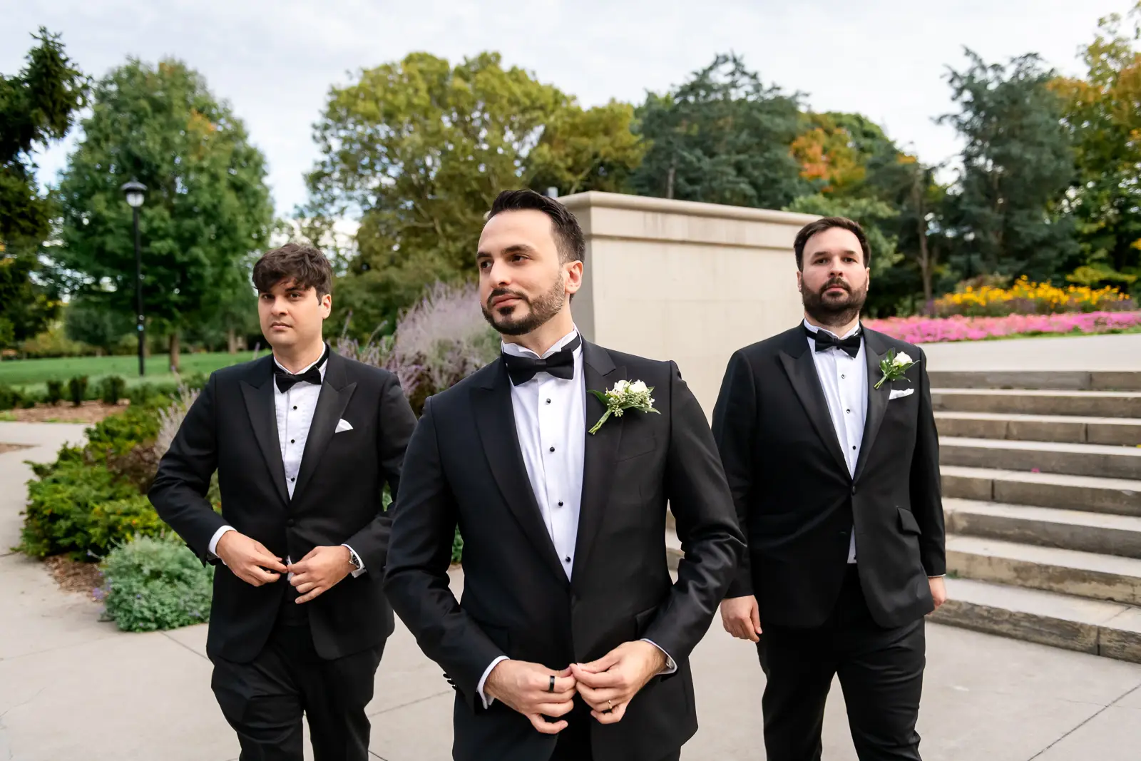 the groom and his groomsmen stylishly walk towards the camera. Shot at Hamilton's Gage Park by Pixelesque Photography.