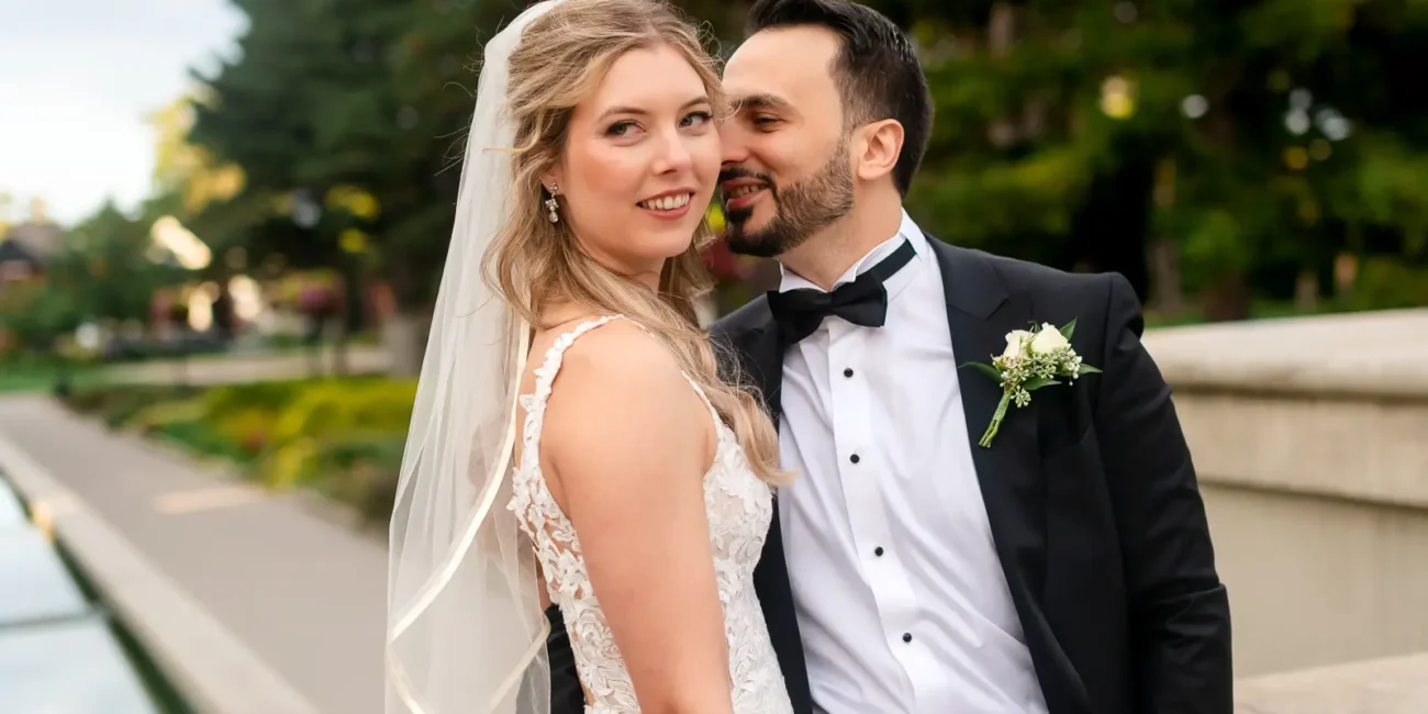 the groom leans in to his bride as she playfully looks away. Shot at Hamilton's Gage Park by Pixelesque Photography.