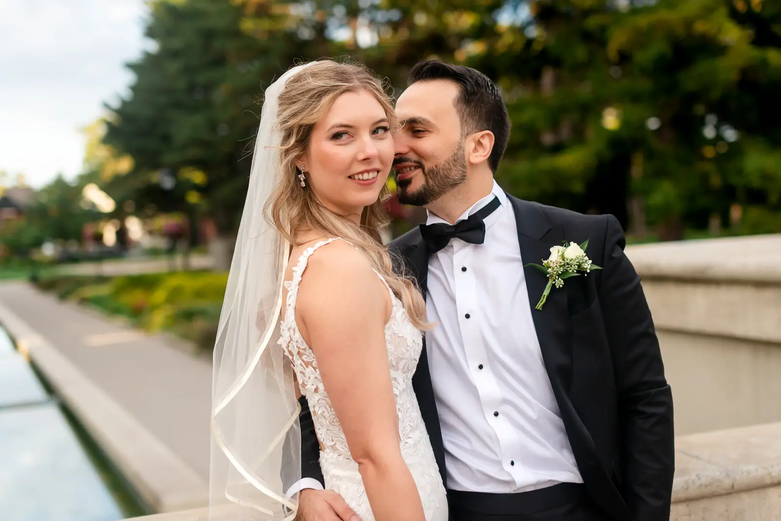 the groom leans in to his bride as she playfully looks away. Shot at Hamilton's Gage Park by Pixelesque Photography.