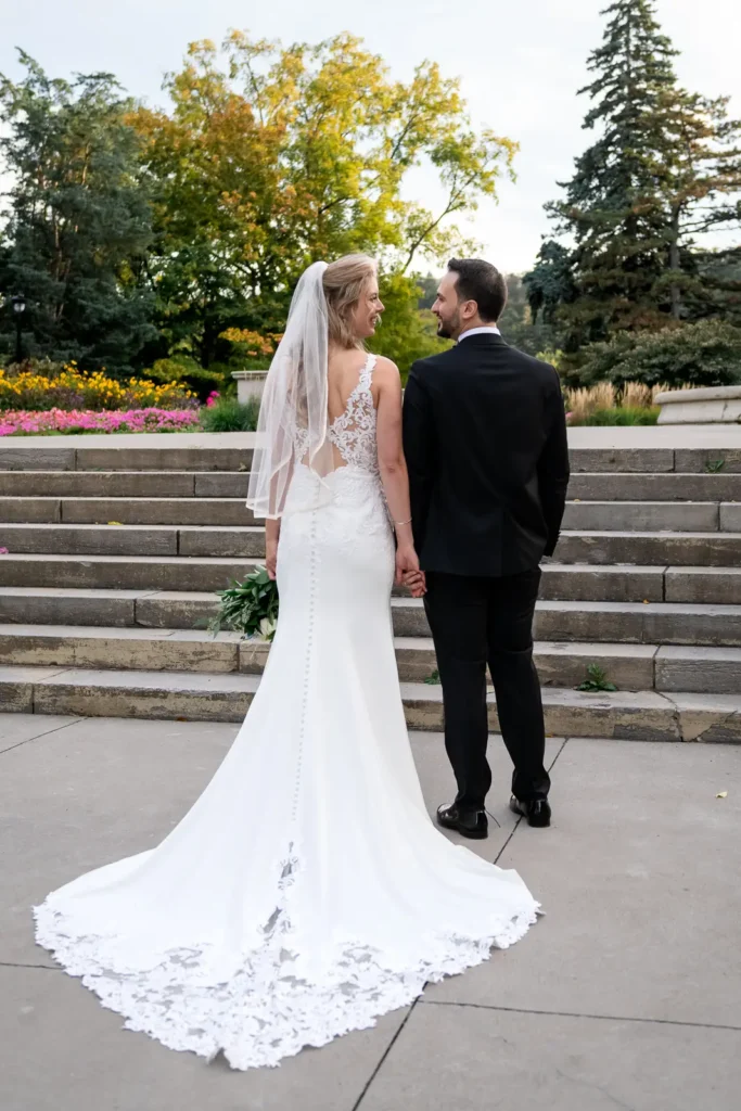 a wedding couple have their back facing the camera and look at each other with stairs ahead of them . Shot at Hamilton's Gage Park by Pixelesque Photography.
