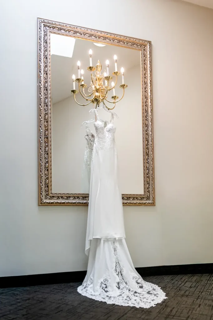 a wedding dress hangs off a light fixture on a mirror. Shot at Carmen's event centre, Hamilton by Pixelesque Photography.