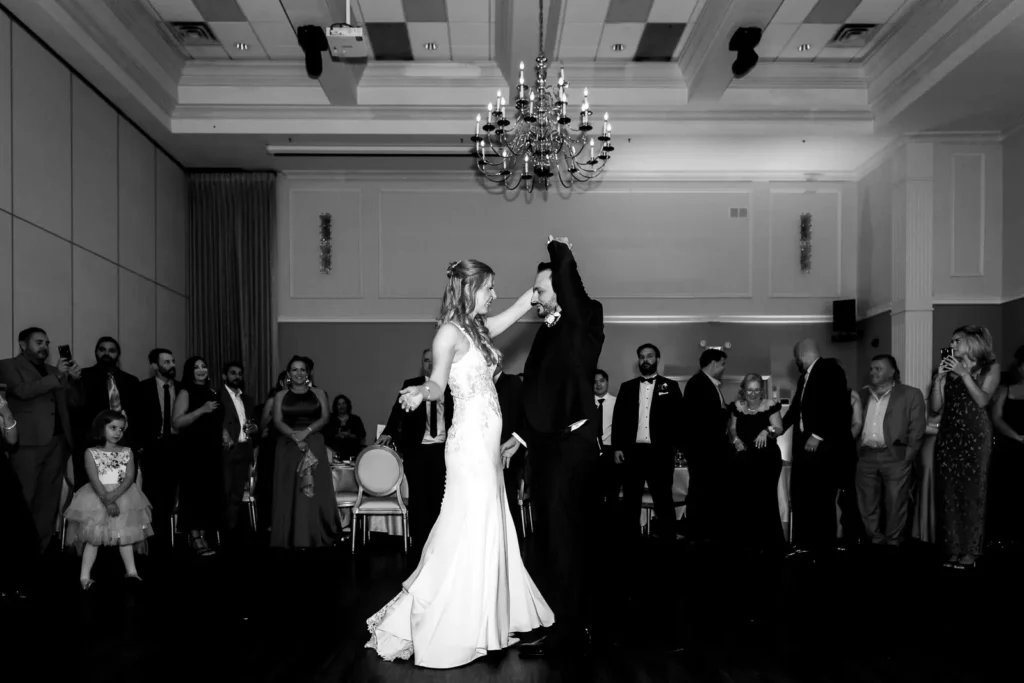 a wedding couple share their first dance as all the guests stand and watch them. Shot at Carmen's Event Centre, Hamilton by Pixelesque Photography.