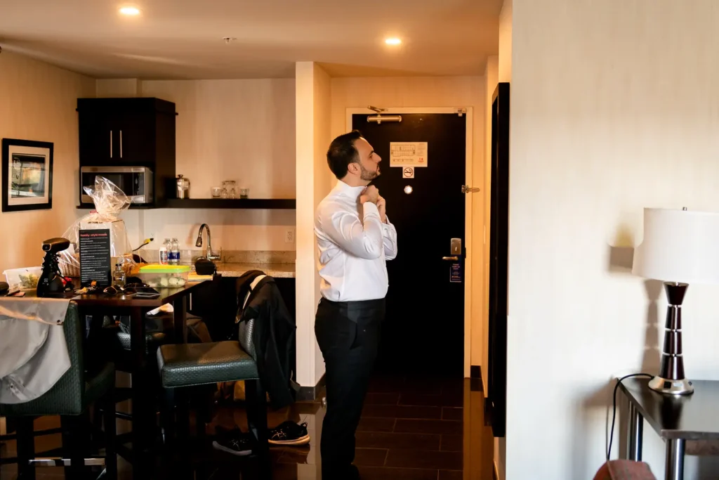the groom fixes his tie while looking in the mirror. Shot in C hotel, Hamilton by Pixelesque Photography.
