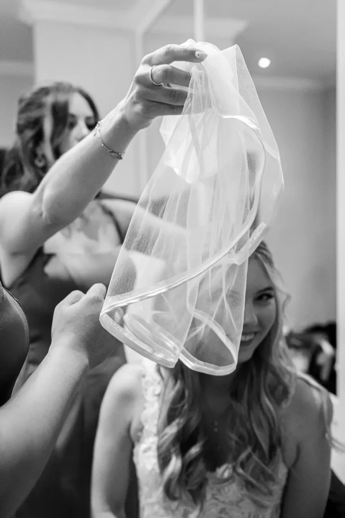 a bridesmaid puts the veil over the bride. Shot at Carmen's event centre, Hamilton by Pixelesque Photography.