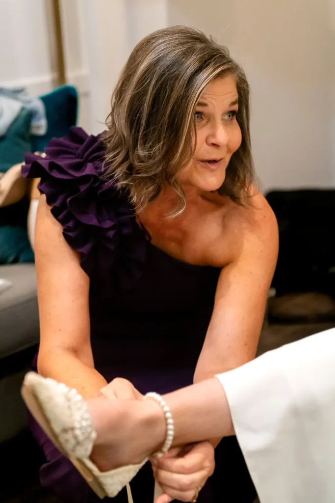the bride's mother helps the bride with her shoe. Shot at Carmen's event centre, Hamilton by Pixelesque Photography.