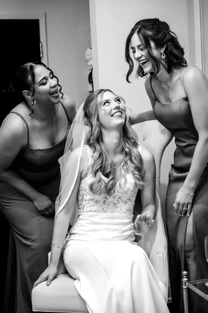 the bridesmaids share a laugh with the bride sat between them. Shot at Carmen's event centre, Hamilton by Pixelesque Photography.