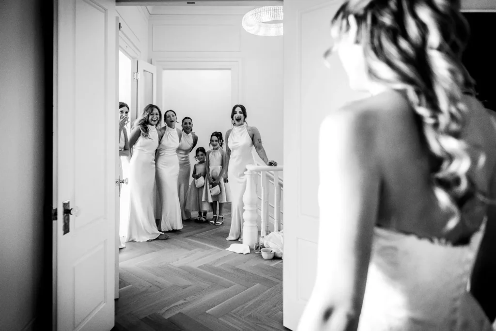 Emotional first look as bridesmaids see bride for the first time.