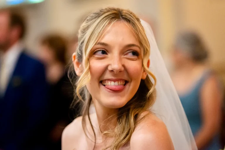 Bride playfully looks towards friends during wedding ceremony at St. Gregory’s Church.