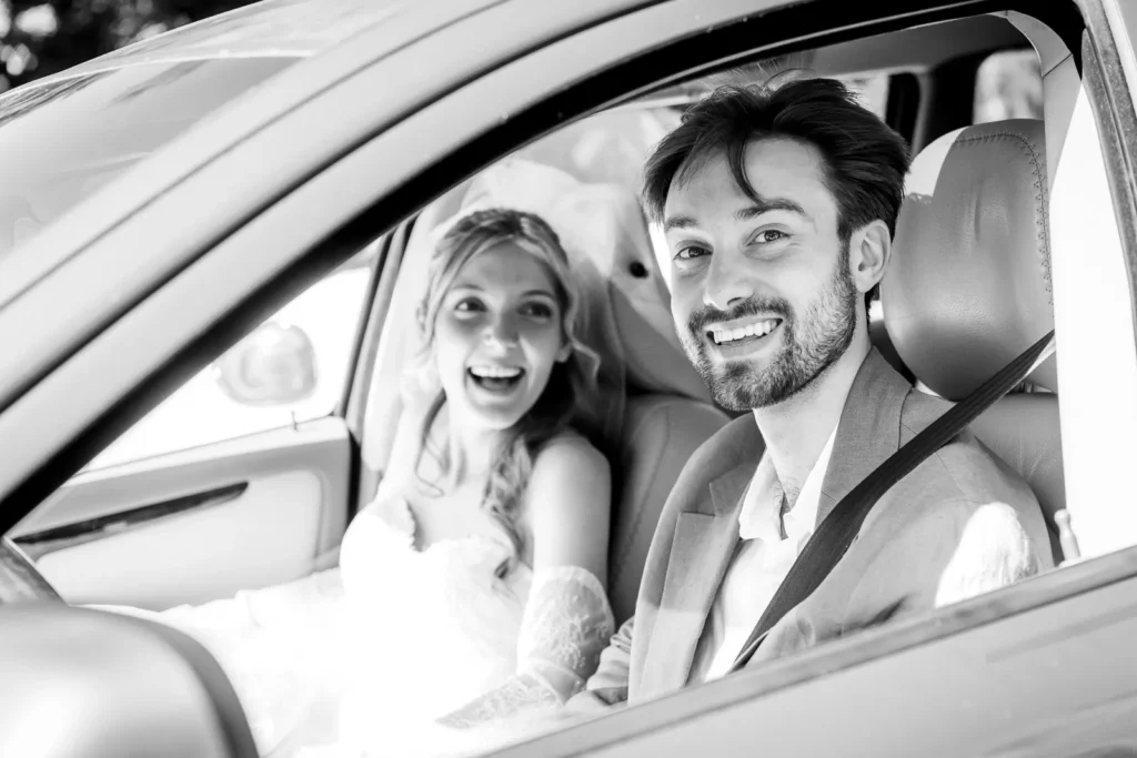 Bride and groom driving away in a decorated Volvo XC70 after the ceremony.
