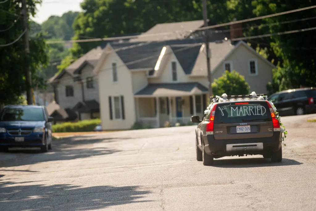 Bride and groom driving away in a decorated Volvo XC70 after the ceremony.