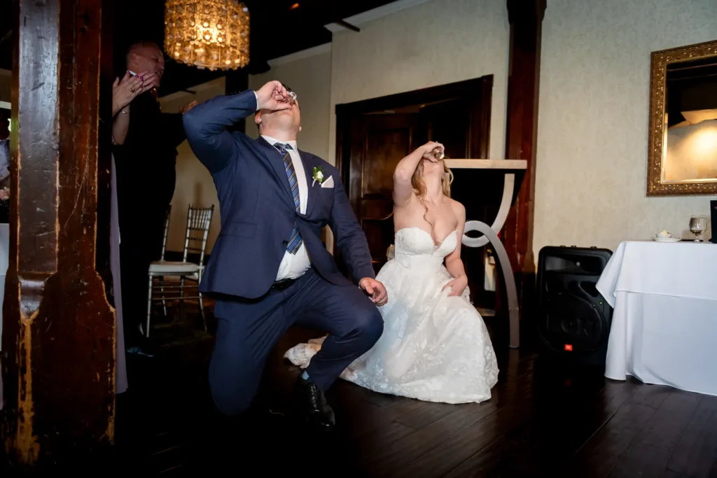 a wedding couple takes a knee and shoots a shot as they enter their reception in the governor's room at Ancaster Mill in Hamilton, Ontario.
