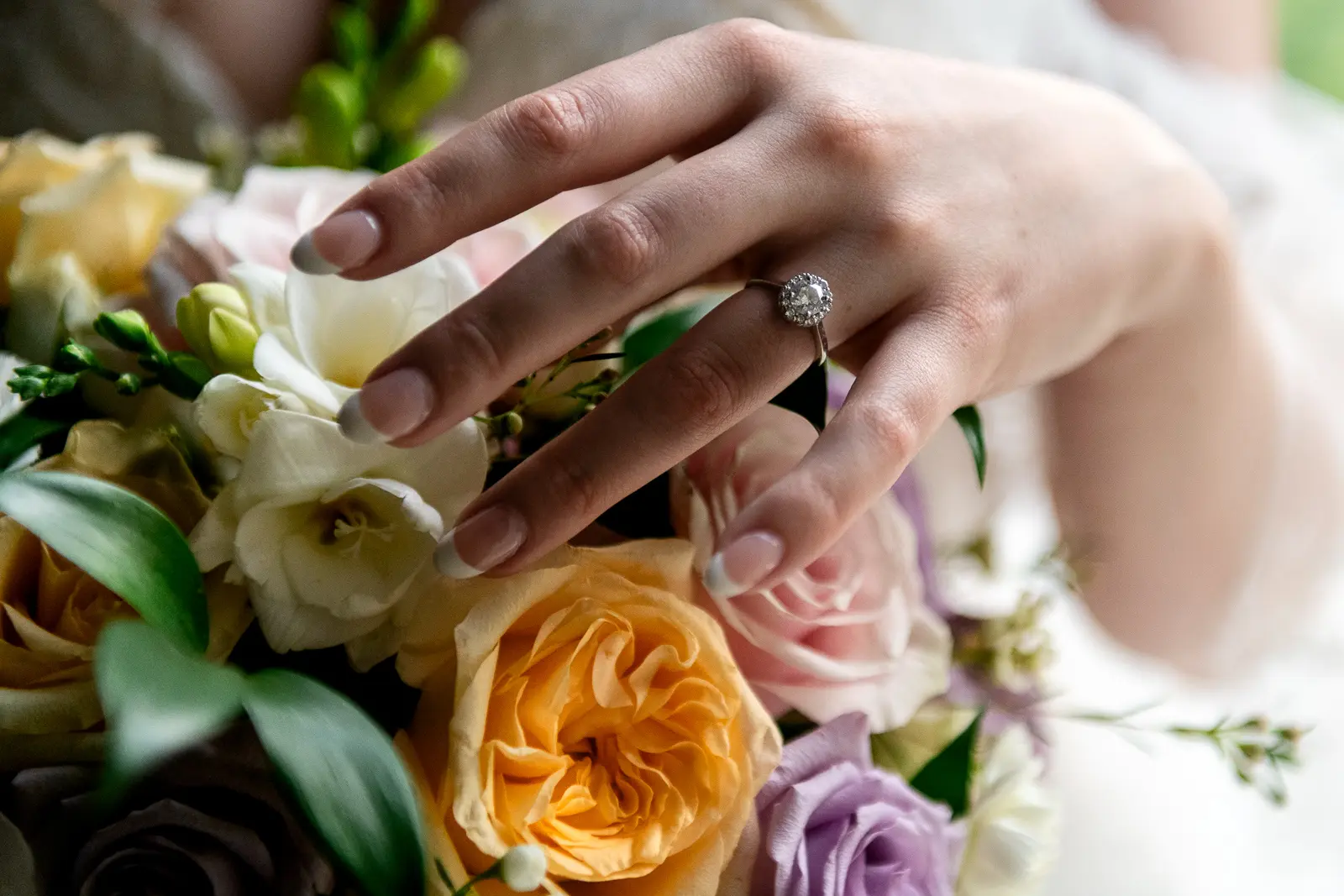 a close up of a bride running her hand over her bouquet at Ancaster Mill in Hamilton, Ontario.