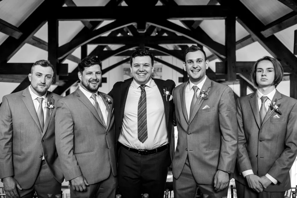 a groom poses with his groomsmen in the loft of the indoor chapel at Ancaster Mill in Hamilton, Ontario.