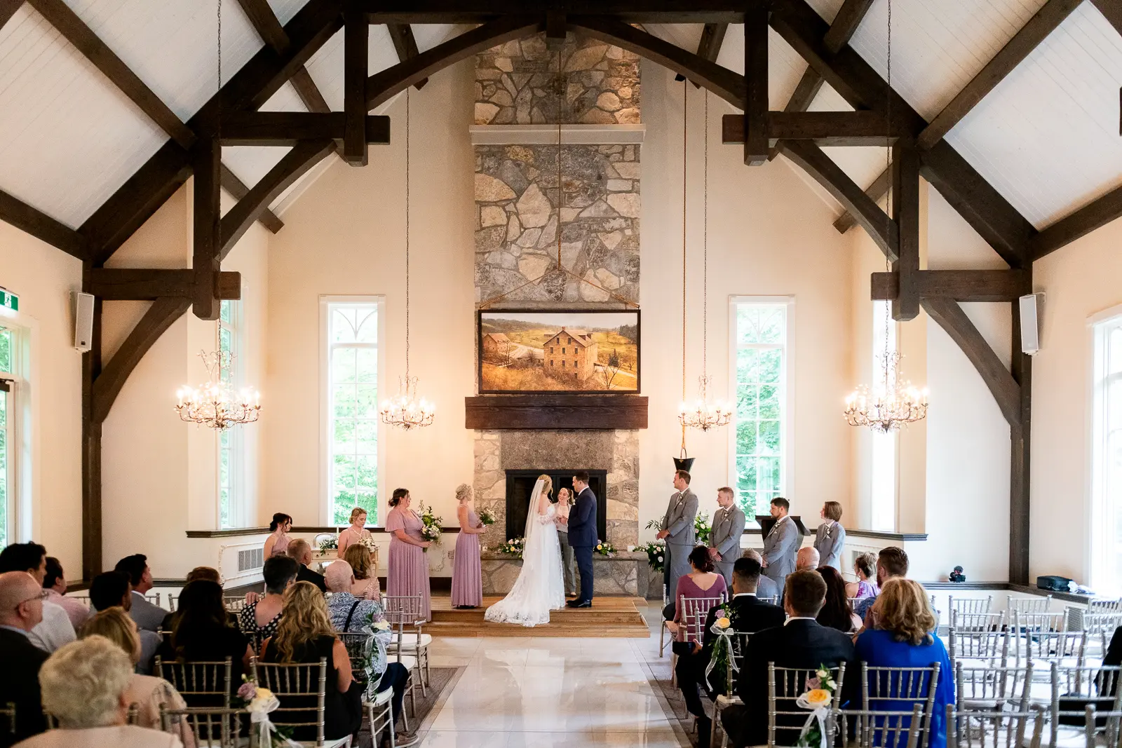 a wide view of the indoor chapel and the wedding couple and bridal party gathered at the altar at Ancaster Mill, Hamilton, Ontario.