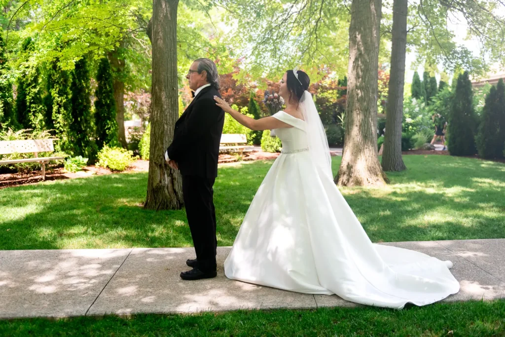 a bride taps her father on his shoulder for their first look at Club Roma in St. Catharines Niagara.
