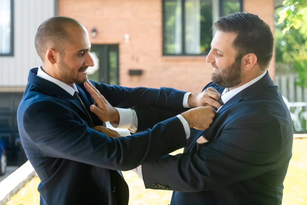 two groomsmen do up each others' ties