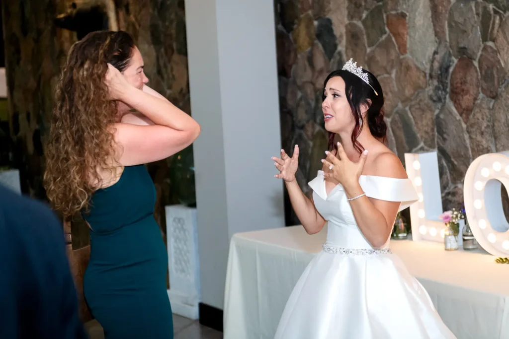 the bride chats with a friend during cocktail hour at Club Roma in St. Catharines Niagara.