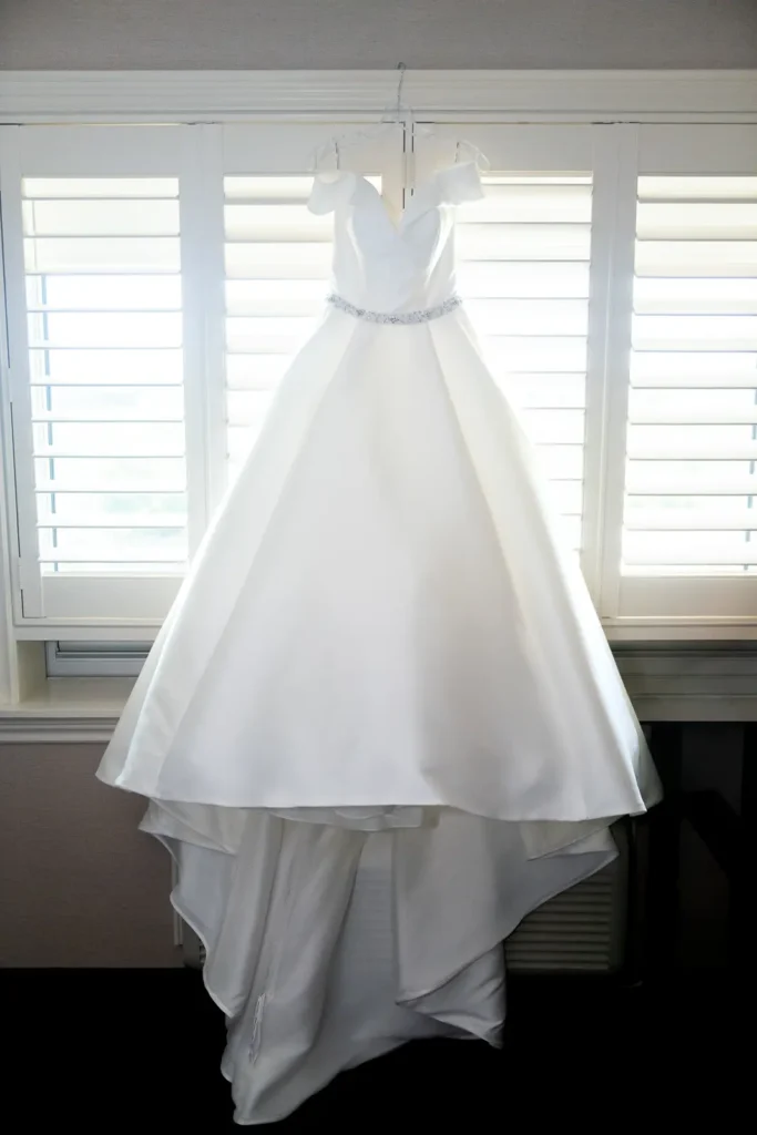 a wedding dress hangs off a hotel window frame