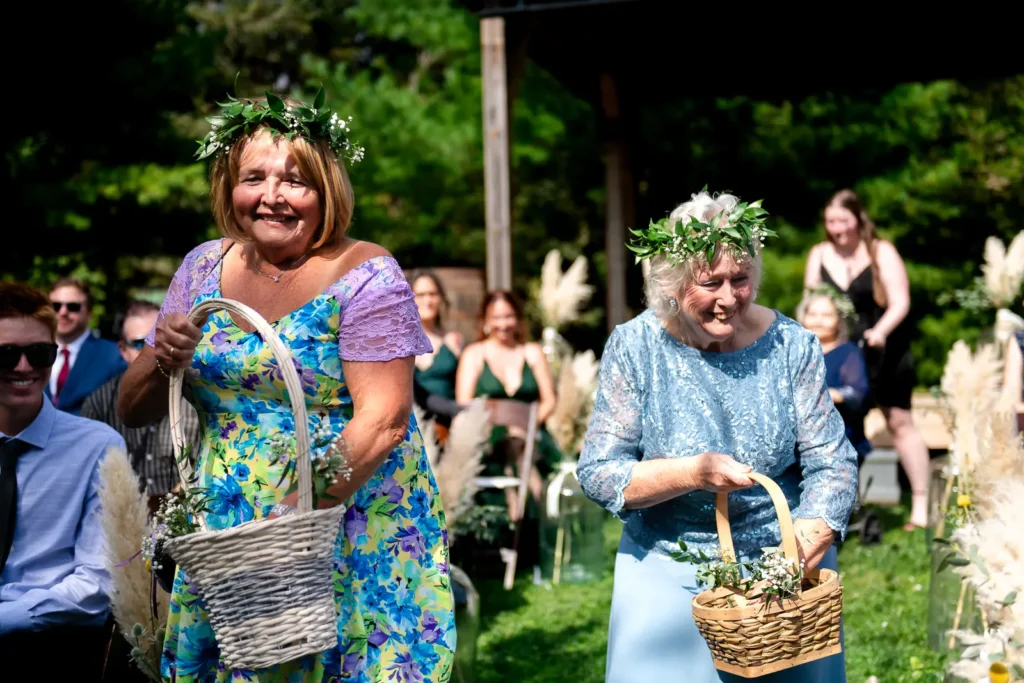 flower grannies wearing flower crowns walk down the wedding aisle and throw petals at Homegrown Hideaway in Norfolk County, Ontario.