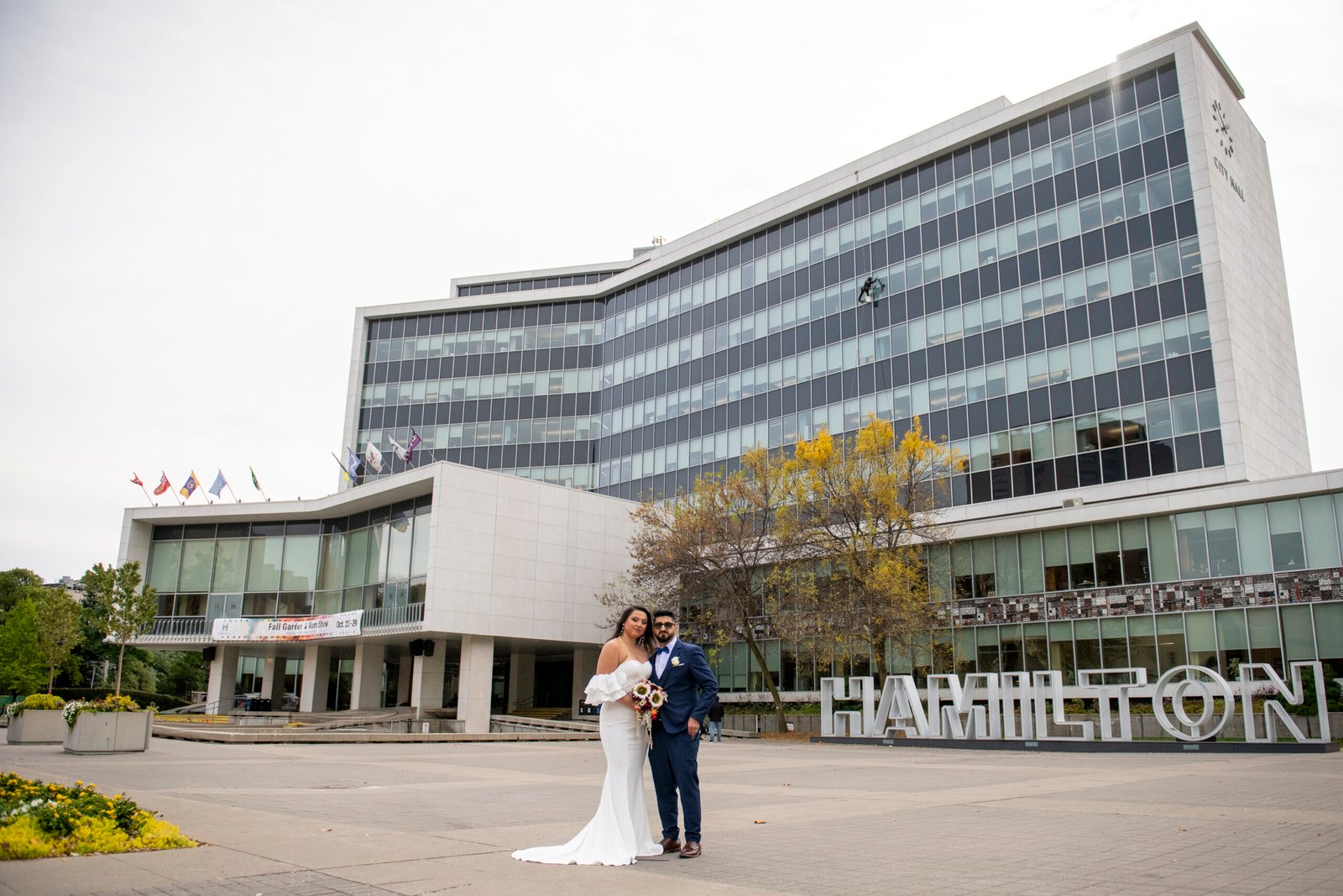 a newly married couple pose outside Hamilton City Hall