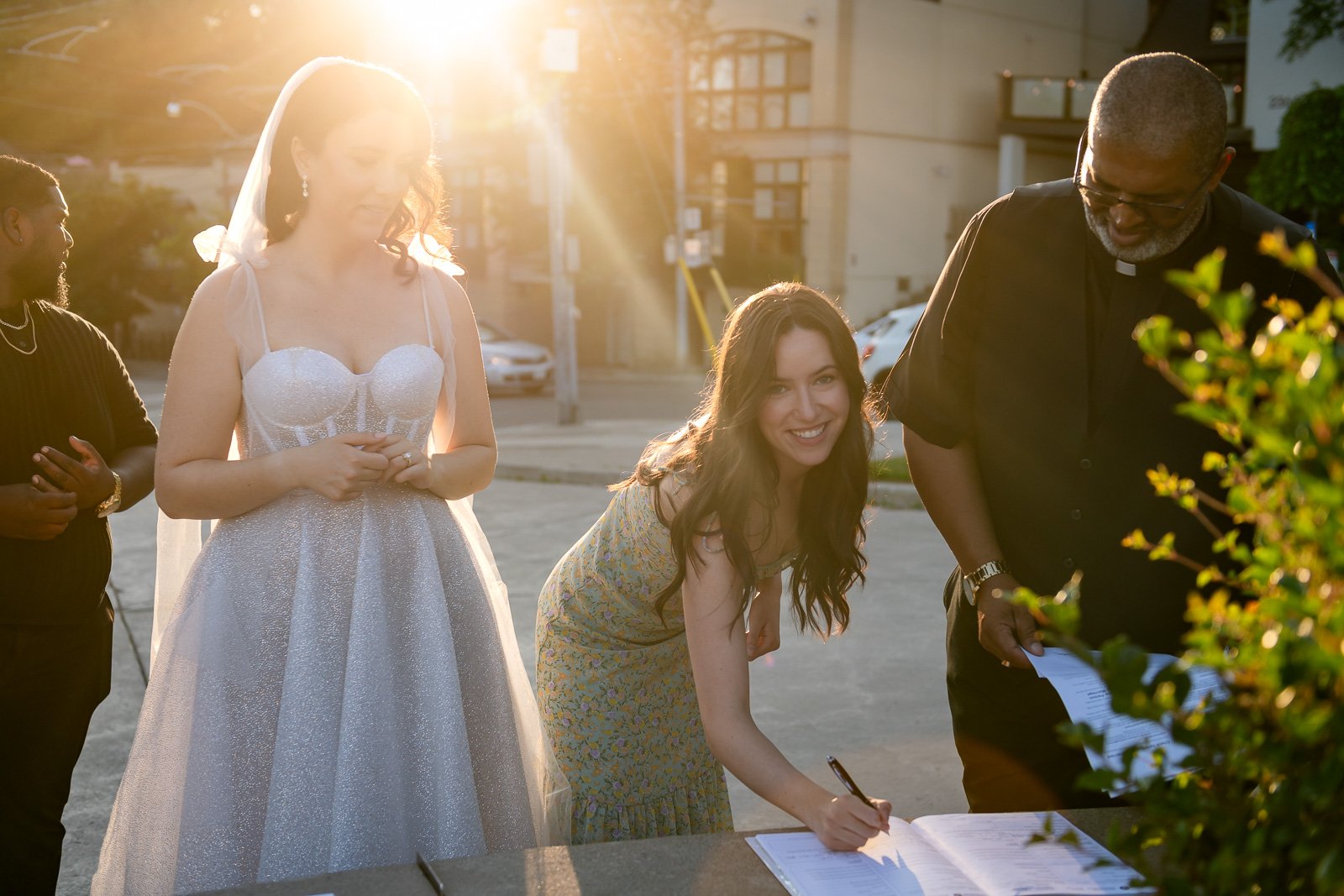 a witness signs the marriage register on the side of the road outside RC Harris water treatment plant in Toronto