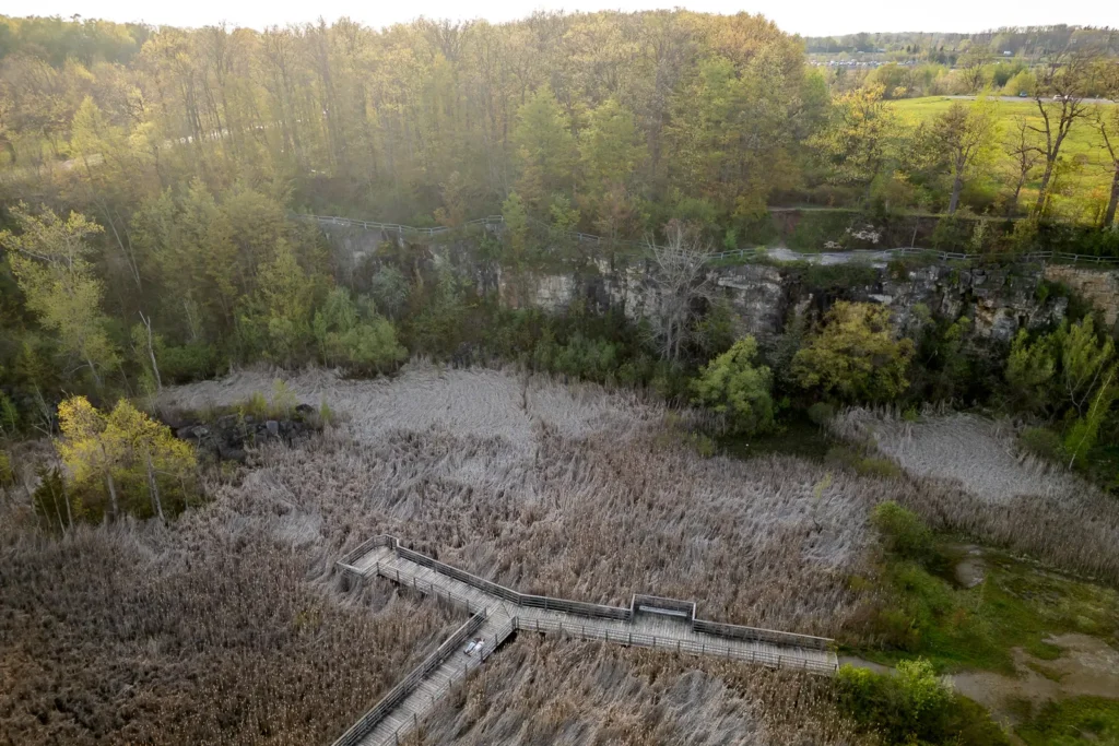 an aerial drone view of the boardwalk at kerncliff park in burlington with the engaged couple laying down